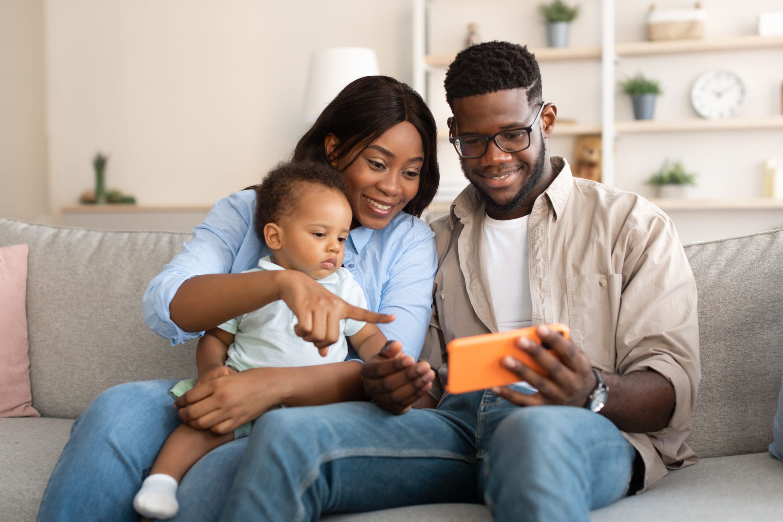 African American Family Using Cellphone With Baby At Home